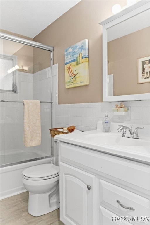 4 S Columbus St, Beverly Hills, FL 34465 - full bathroom featuring vanity, tile walls, shower / bath combination with glass door, and wood finished floors