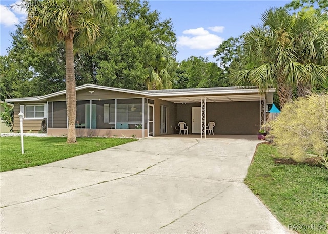 4 S Columbus St, Beverly Hills, FL 34465 - view of front of property with driveway, an attached carport, a front yard, and a sunroom
