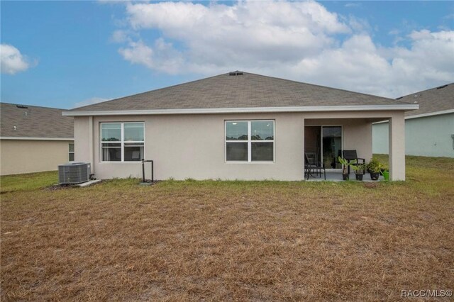 rear view of house with cooling unit and a yard