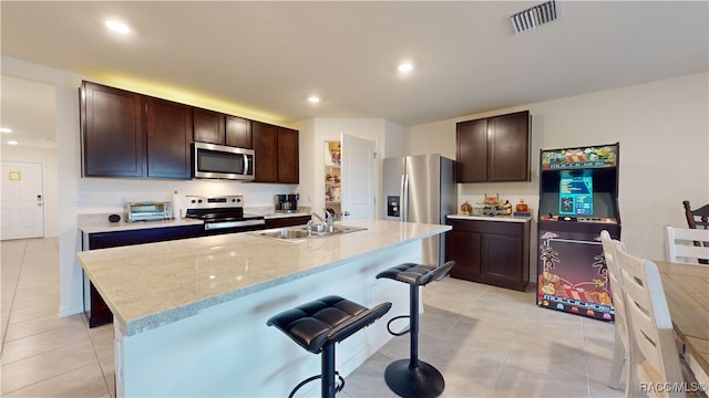 kitchen featuring appliances with stainless steel finishes, a center island with sink, dark brown cabinets, and sink