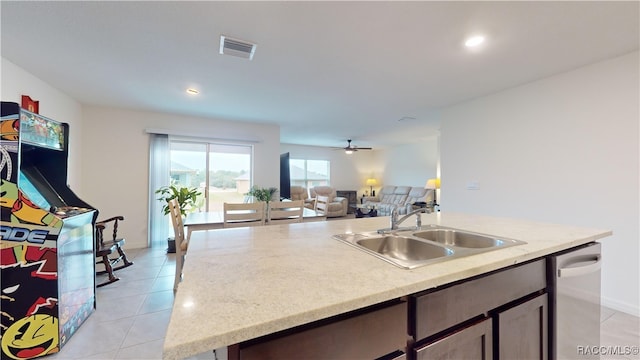 kitchen with ceiling fan, sink, stainless steel dishwasher, a kitchen island with sink, and light tile patterned floors