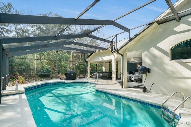 view of swimming pool featuring ceiling fan, a patio area, and glass enclosure