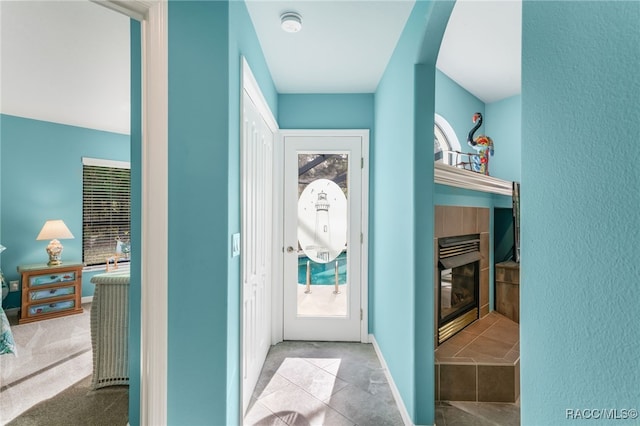 doorway to outside featuring a tiled fireplace and light carpet