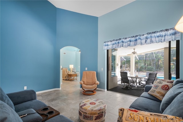 living room with ceiling fan and a high ceiling