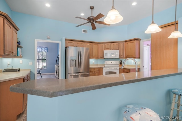 kitchen featuring sink, a breakfast bar area, hanging light fixtures, ceiling fan, and white appliances