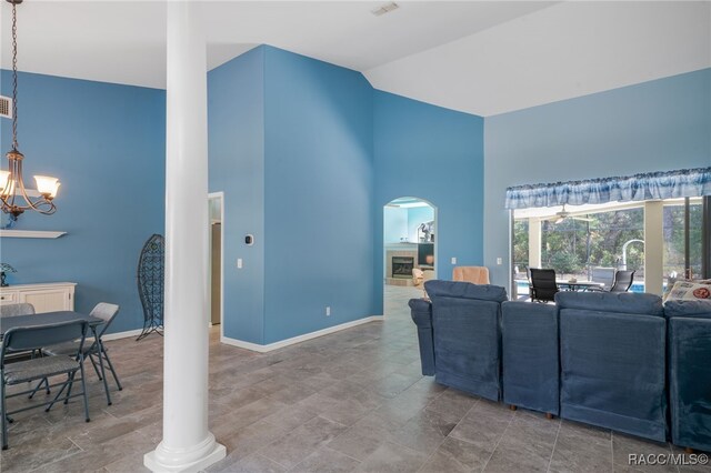 living room featuring an inviting chandelier, high vaulted ceiling, and ornate columns