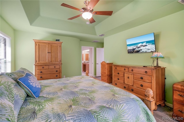 bedroom with a tray ceiling, ceiling fan, and ensuite bathroom