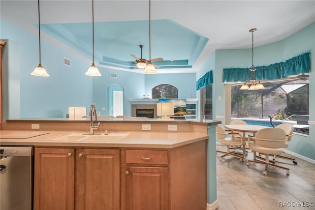 kitchen with sink, ceiling fan, hanging light fixtures, stainless steel dishwasher, and a raised ceiling