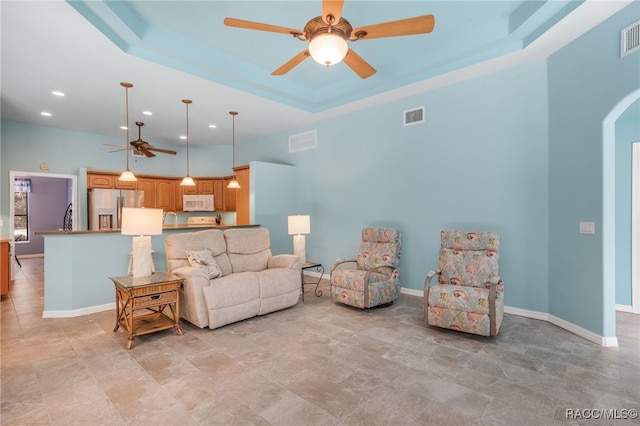 living room with a raised ceiling and ceiling fan