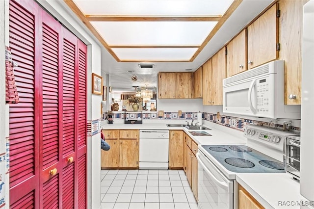 kitchen featuring white appliances, light countertops, a sink, and light tile patterned floors