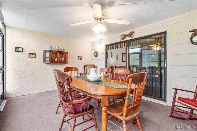 dining space featuring a textured ceiling, a textured wall, carpet floors, and a ceiling fan