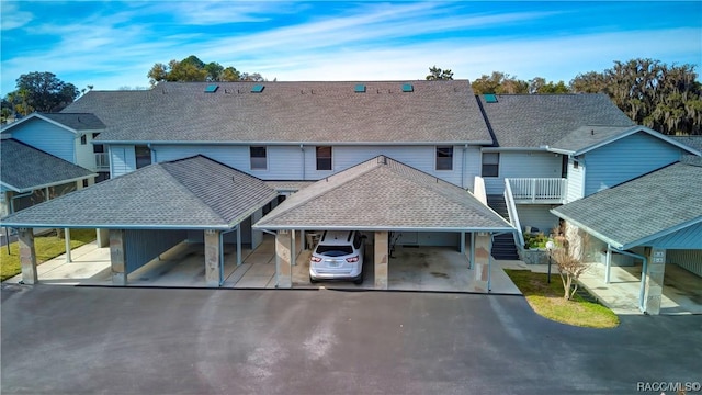 townhome / multi-family property with an attached carport and roof with shingles