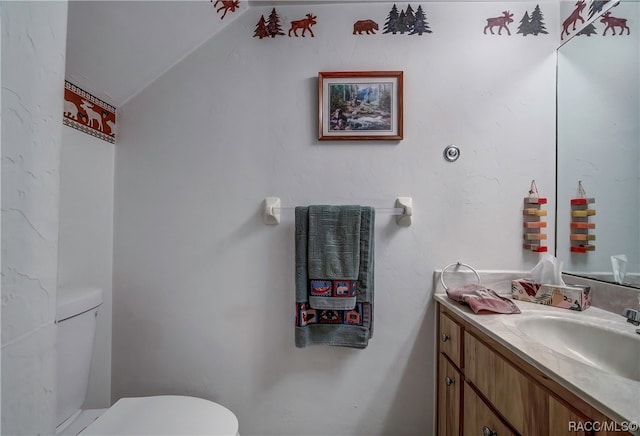 bathroom with vanity, toilet, and lofted ceiling