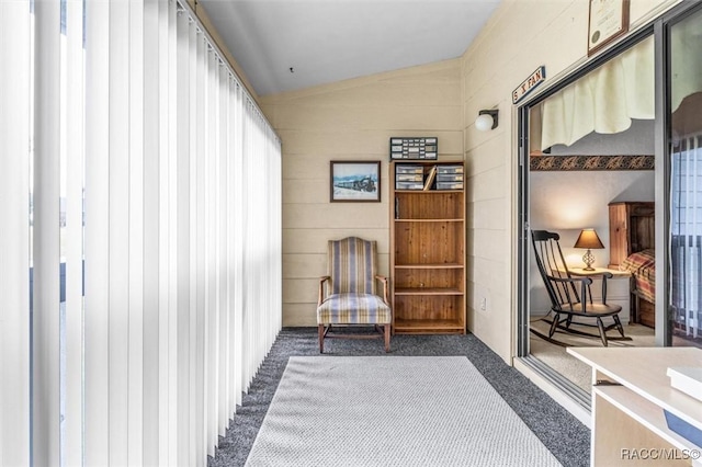 sitting room with lofted ceiling and dark colored carpet