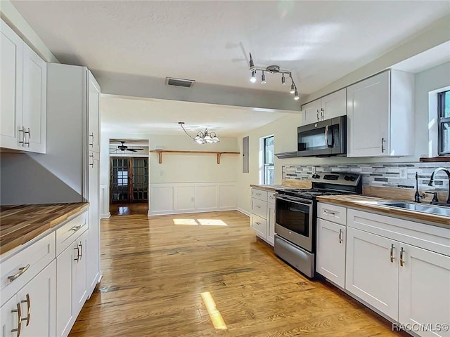 kitchen featuring sink, light wood-type flooring, white cabinets, and appliances with stainless steel finishes