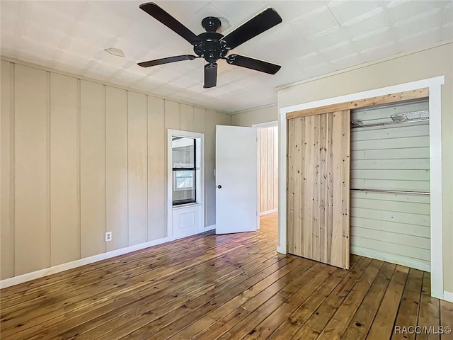 unfurnished bedroom featuring dark wood-type flooring, a closet, and ceiling fan