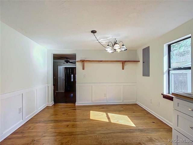 unfurnished dining area with a chandelier, electric panel, and light hardwood / wood-style floors