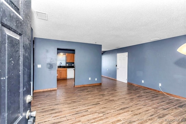 unfurnished living room featuring sink, a textured ceiling, and hardwood / wood-style flooring