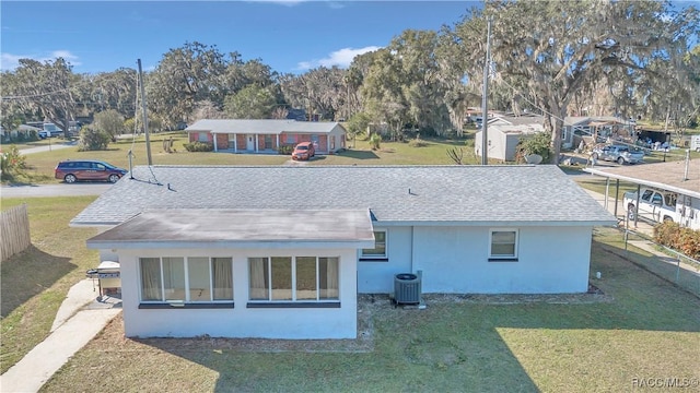 rear view of house featuring a lawn and central AC unit