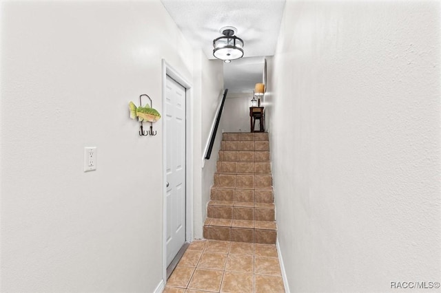 stairway with baseboards and tile patterned floors