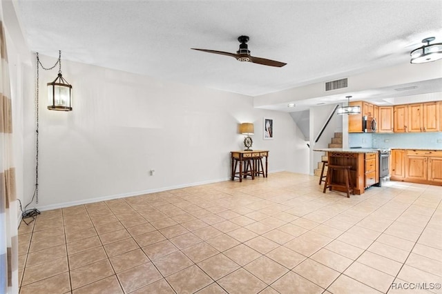 kitchen with visible vents, appliances with stainless steel finishes, hanging light fixtures, light countertops, and a kitchen bar