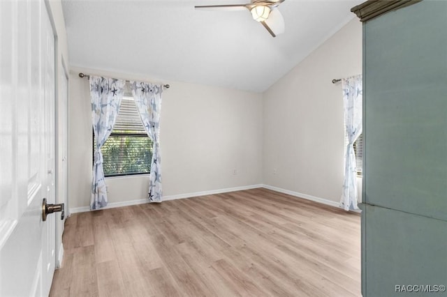 spare room with vaulted ceiling, light wood-style flooring, baseboards, and ceiling fan