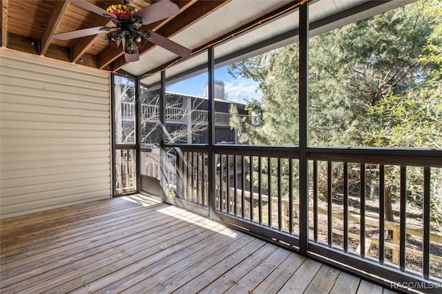 unfurnished sunroom featuring beam ceiling and ceiling fan