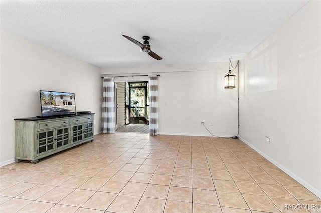 unfurnished living room with ceiling fan, light tile patterned floors, a textured ceiling, and baseboards