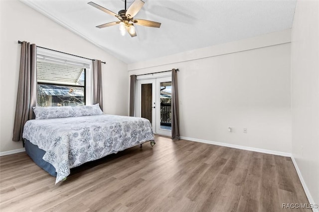 bedroom with access to outside, lofted ceiling, baseboards, and wood finished floors