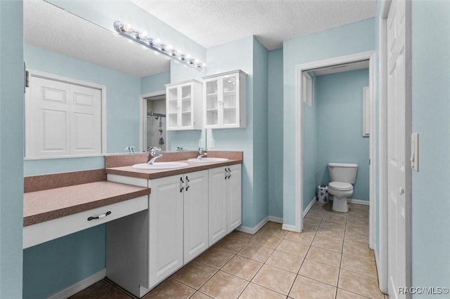 bathroom featuring double vanity, tile patterned flooring, a textured ceiling, and a sink