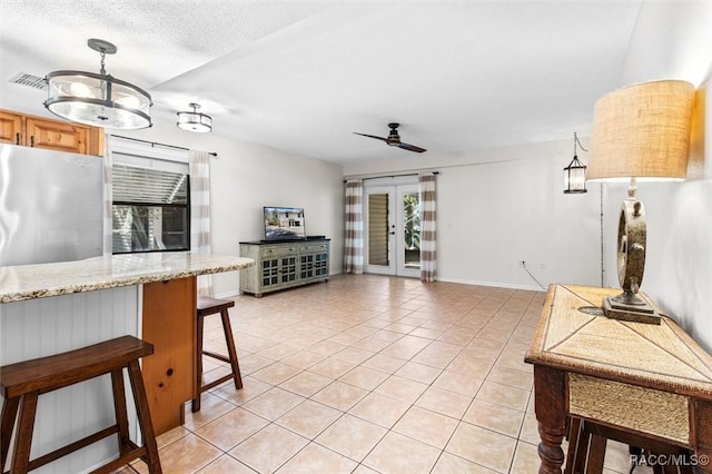 kitchen featuring light tile patterned flooring, a breakfast bar, visible vents, open floor plan, and freestanding refrigerator