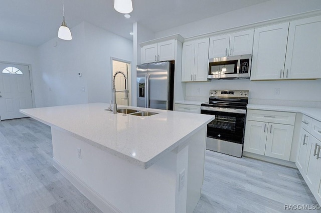 kitchen with white cabinetry, sink, stainless steel appliances, pendant lighting, and a center island with sink