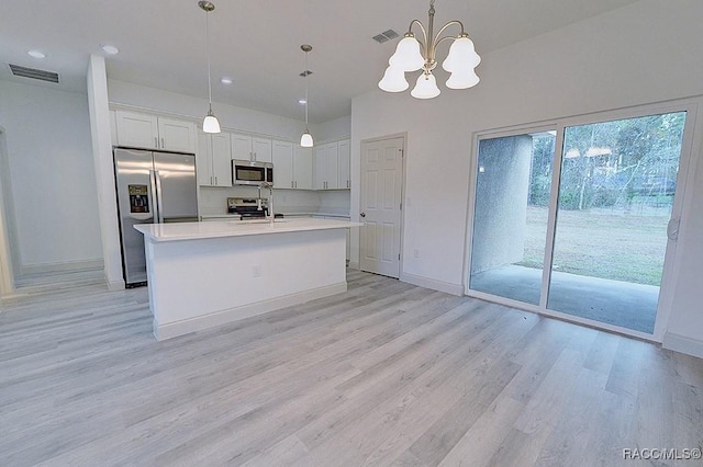 kitchen with white cabinets, light hardwood / wood-style floors, decorative light fixtures, and appliances with stainless steel finishes