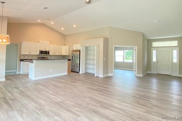 653 E Connecticut Ln, Hernando, FL 34442 - kitchen with appliances with stainless steel finishes, open floor plan, high vaulted ceiling, light wood-style floors, and white cabinets