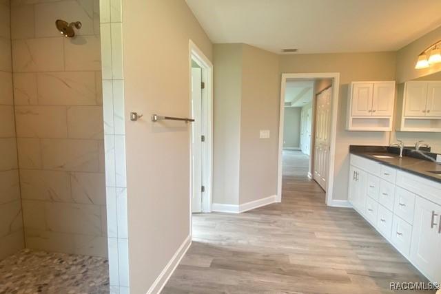 653 E Connecticut Ln, Hernando, FL 34442 - bathroom with double vanity, a tile shower, and wood finished floors