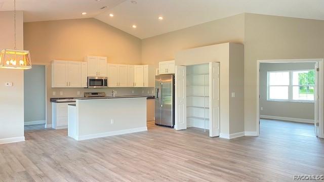 653 E Connecticut Ln, Hernando, FL 34442 - kitchen with stainless steel appliances, high vaulted ceiling, light wood finished floors, white cabinets, and an island with sink