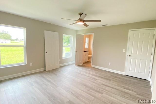 653 E Connecticut Ln, Hernando, FL 34442 - unfurnished bedroom featuring light wood-style flooring, ceiling fan, and ensuite bathroom