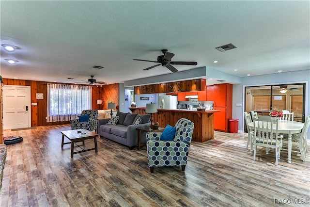 living room featuring dark hardwood / wood-style flooring, a textured ceiling, and wood walls