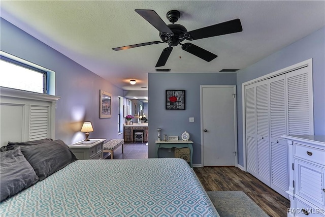 bedroom with ensuite bath, ceiling fan, a closet, and dark hardwood / wood-style flooring