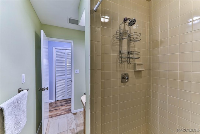 bathroom featuring a tile shower and wood-type flooring