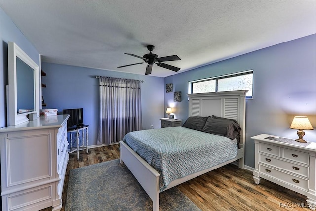 bedroom with a textured ceiling, ceiling fan, and dark hardwood / wood-style floors