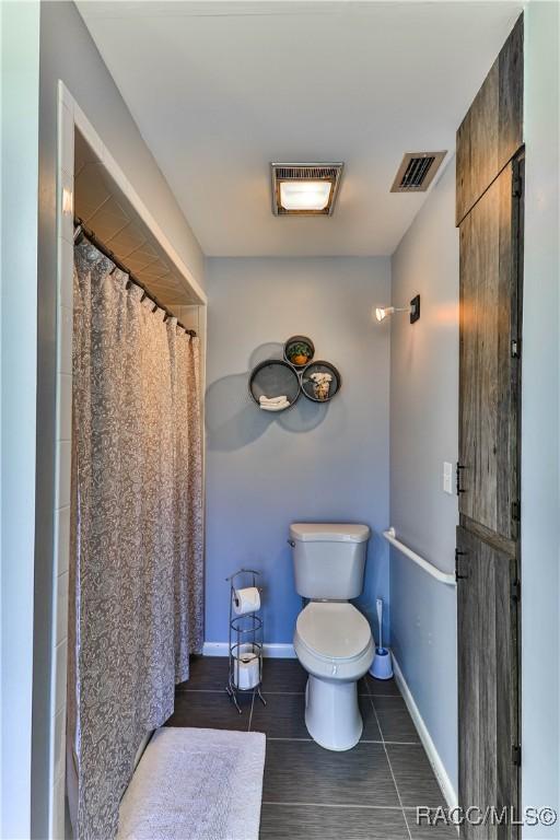 bathroom with tile patterned flooring, a shower with curtain, and toilet