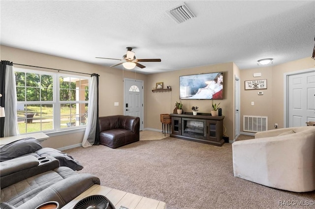 living area featuring visible vents, a textured ceiling, a ceiling fan, and carpet floors