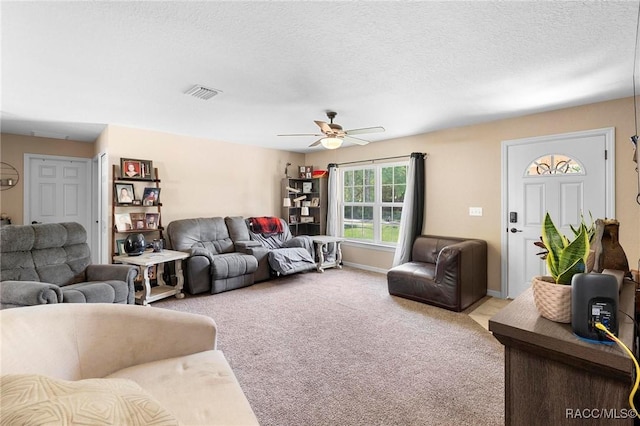 living room with visible vents, baseboards, a ceiling fan, a textured ceiling, and light colored carpet