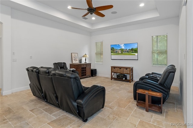 living area with recessed lighting, a raised ceiling, stone tile flooring, and baseboards