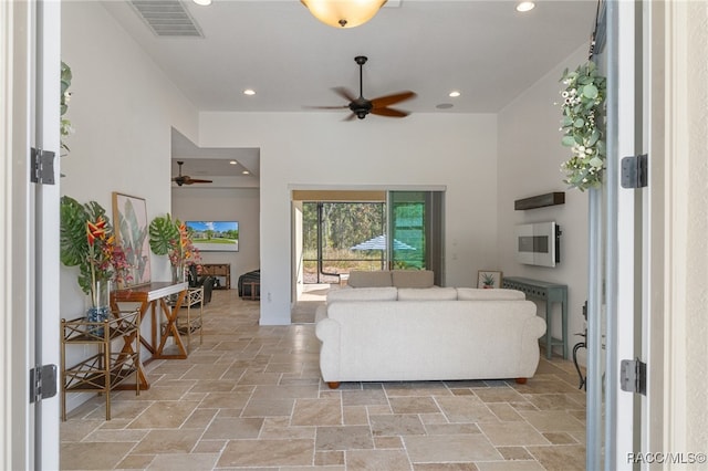 living area with a ceiling fan, visible vents, stone tile flooring, and recessed lighting