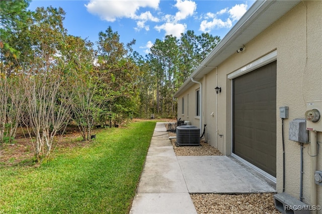 view of yard with a garage and central AC unit