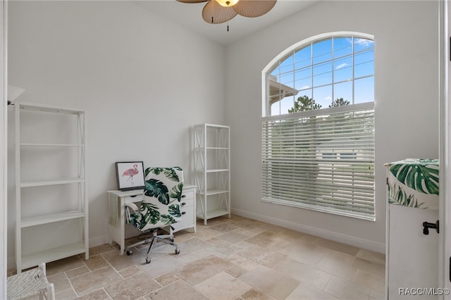 home office with stone finish floor, ceiling fan, and baseboards