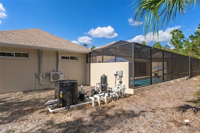 exterior space with a shingled roof, ac unit, a lanai, and stucco siding