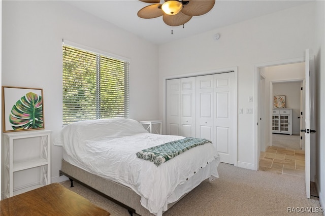 bedroom featuring a ceiling fan, a closet, light colored carpet, and baseboards